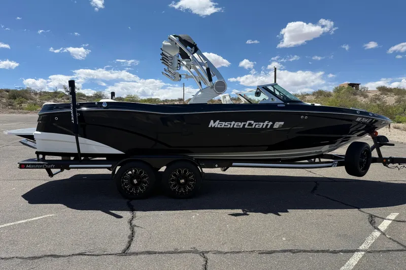 The Image of 2018 MasterCraft XT25 boat on trailer under a clear blue sky. - 0