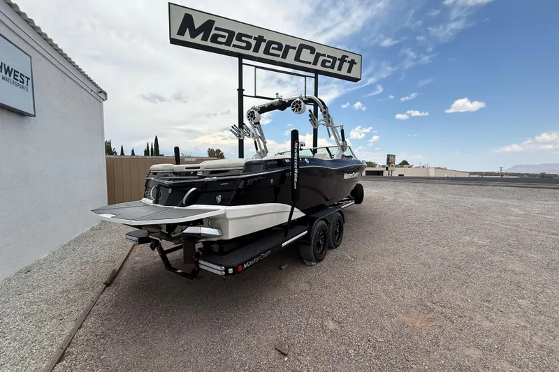 Slide: The Image of 2018 MasterCraft XT25 boat on trailer at dealership under clear sky. - 11
