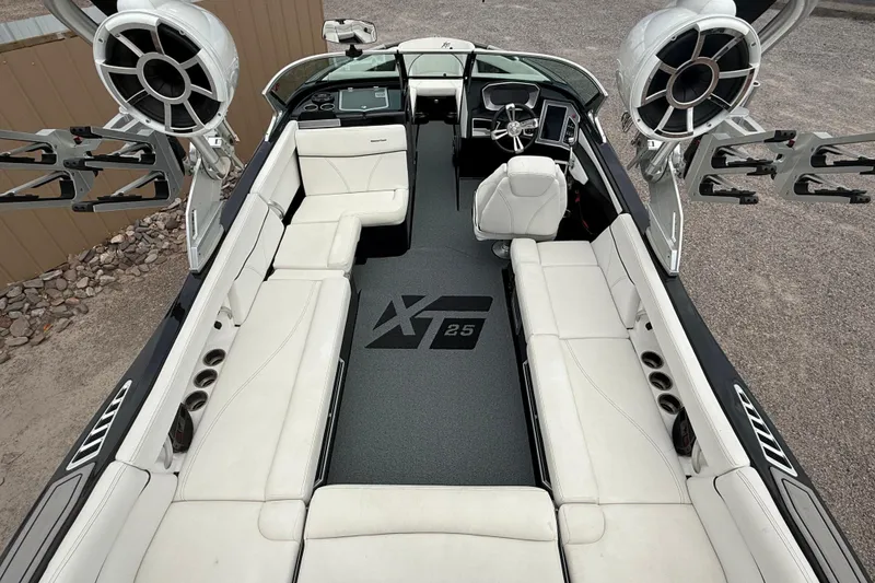 Slide: The Image of 2018 MasterCraft XT25 boat interior with white seating and advanced audio system. - 13