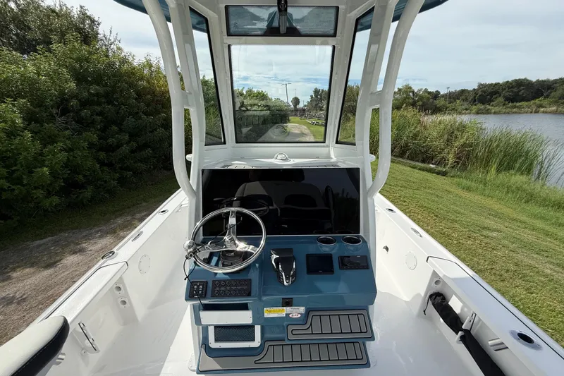 Slide: The Image of 2026 Tidewater 2410 Bay Max boat console with steering wheel, controls, and scenic waterway view. - 13