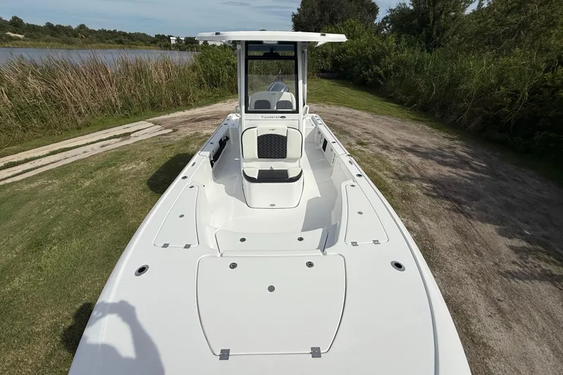 Slide: The Image of 2026 Tidewater 2410 Bay Max boat on grassy shore near water and trees. - 17