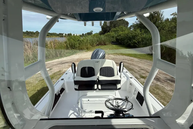Slide: The Image of 2026 Tidewater 2410 Bay Max boat interior with dual seats and steering wheel, near a scenic waterway. - 19
