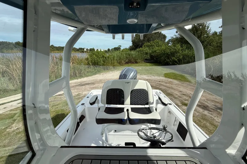 Slide: The Image of 2026 Tidewater 2410 Bay Max boat interior with dual seats and steering wheel, near a scenic waterway. - 20