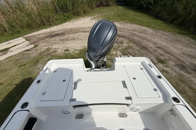 Slide: The Image of 2026 Tidewater 2410 Bay Max boat with outboard motor, parked on grassy terrain. - 21