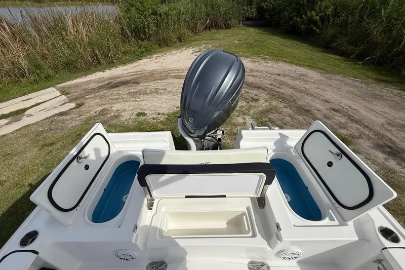Slide: The Image of 2026 Tidewater 2410 Bay Max boat with open storage compartments and outboard motor. - 23