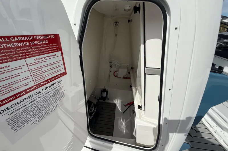 Slide: The Image of 2026 Tidewater 2410 Bay Max boat storage compartment with safety and discharge instructions. - 33