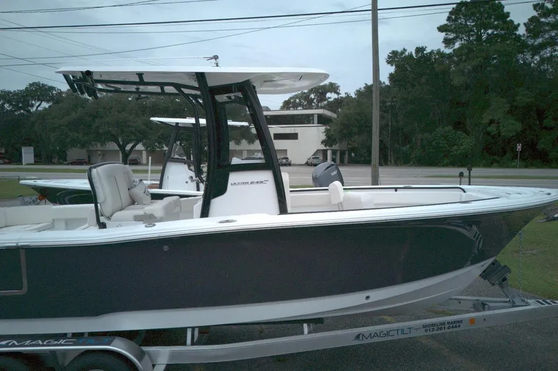 Slide: The Image of 2026 Seahunt 245 boat on trailer, parked outdoors near trees and buildings. - 11