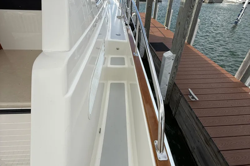 Slide: The Image of 2017 Grand Banks 44 Eastbay SX yacht with striped seating, red cushions, and wooden deck. - 35