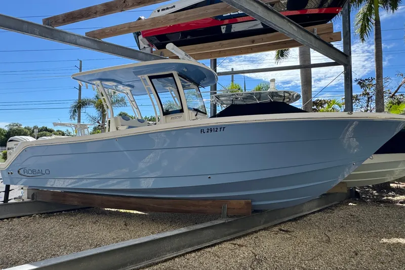 The Image of 2023 Robalo R302 Center Console boat in light blue, displayed on a rack outdoors. - 1