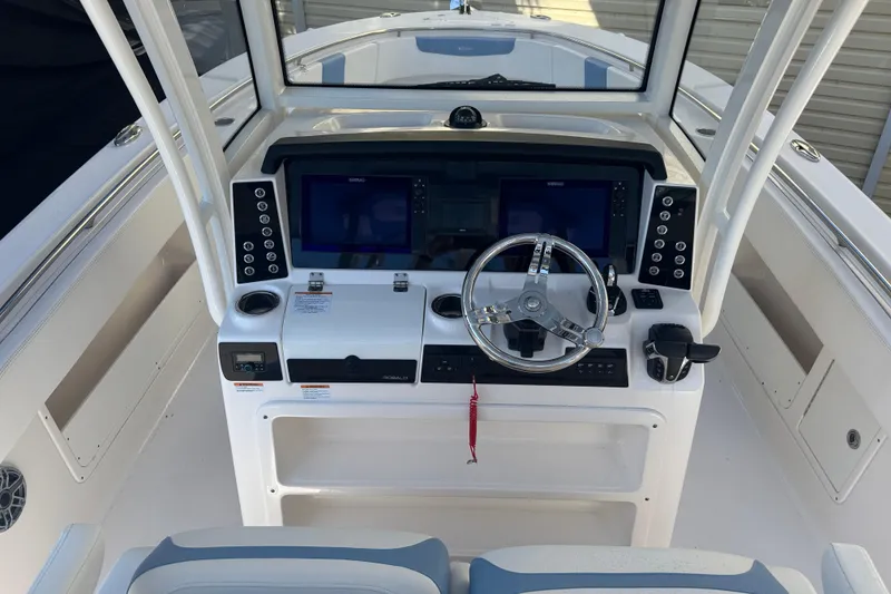 Slide: The Image of 2023 Robalo R302 Center Console boat dashboard with steering wheel and navigation screens. - 6