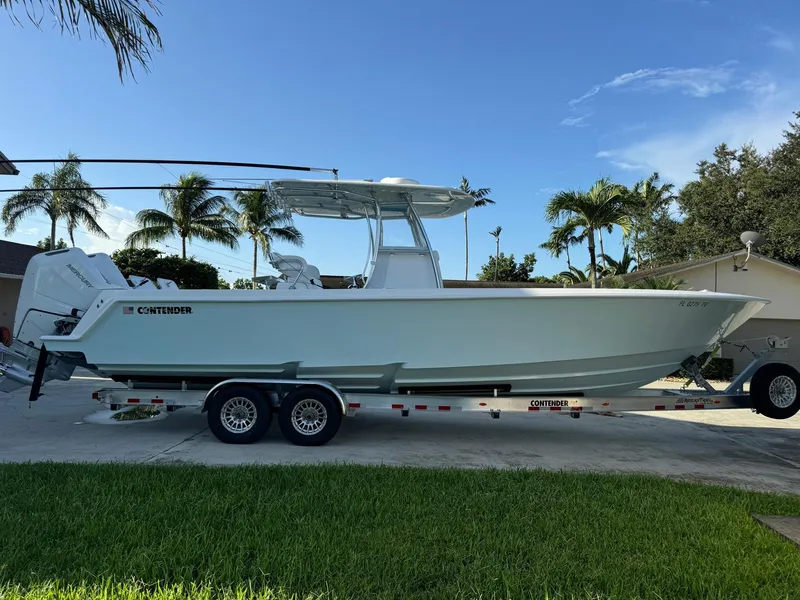 Slide: The Image of 2024 Contender 32 ST boat on trailer, parked outdoors with palm trees in background. - 1