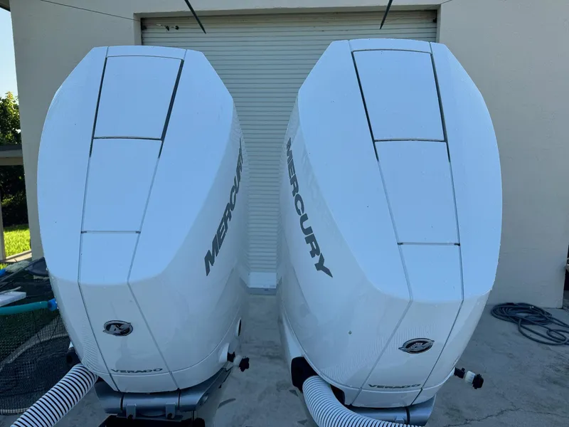 Slide: The Image of Twin Mercury outboard engines on a 2024 Contender 32 ST boat, parked near a garage. - 13