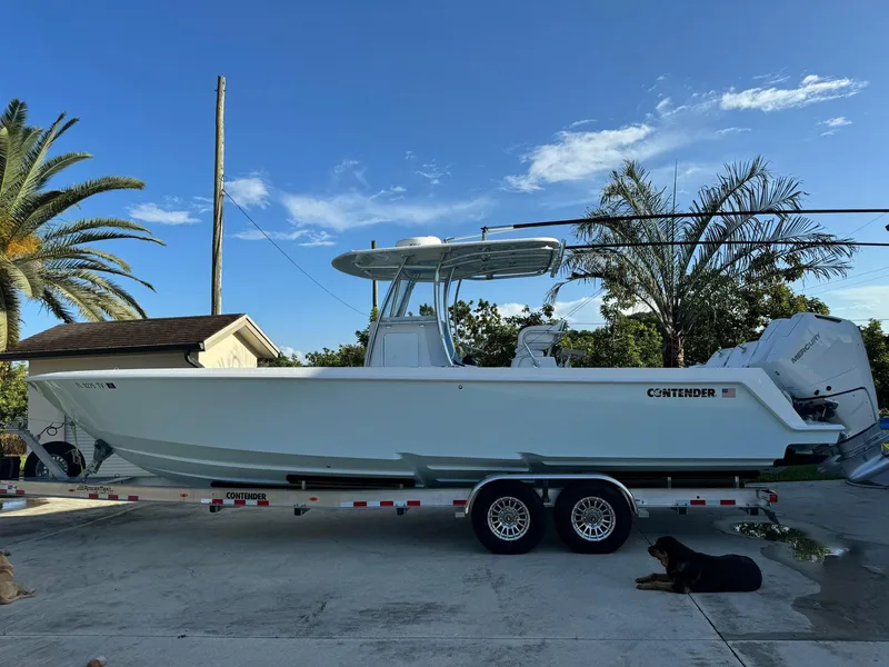 Slide: The Image of 2024 Contender 32 ST boat on trailer, parked outdoors with palm trees in the background. - 16