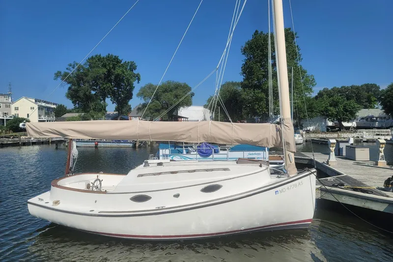 The Image of 1983 Atlantic City Kitty Kat 21 sailboat docked in a marina under clear blue skies. - 1