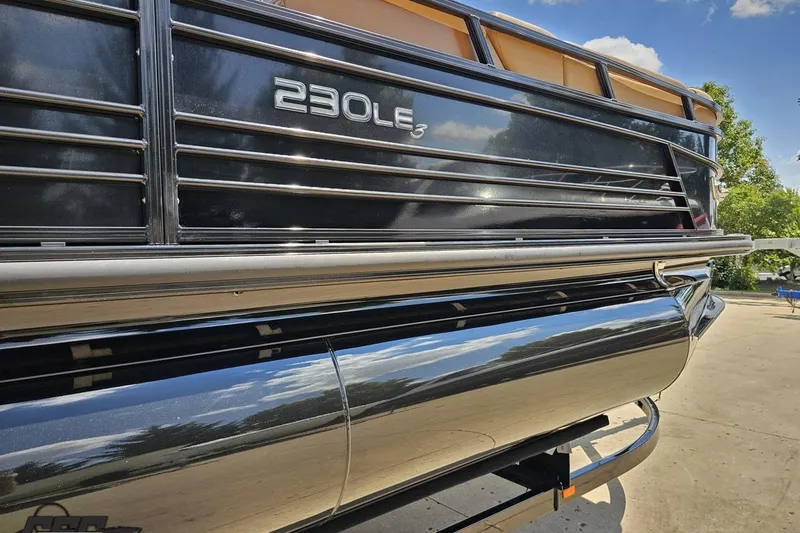 Slide: The Image of 2021 Regency 230 LE3 pontoon boat, sleek design, reflective surface, sunny day. - 11