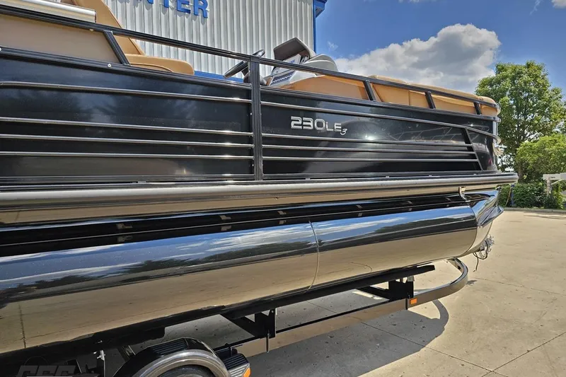 Slide: The Image of 2021 Regency 230 LE3 pontoon boat on trailer, outdoor setting. - 12