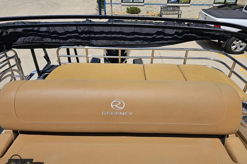 Slide: The Image of 2021 Regency 230 LE3 boat with tan seating and logo, docked outdoors. - 120