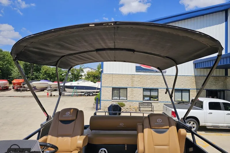 Slide: The Image of 2021 Regency 230 LE3 boat with canopy, parked outside a building under a clear sky. - 124
