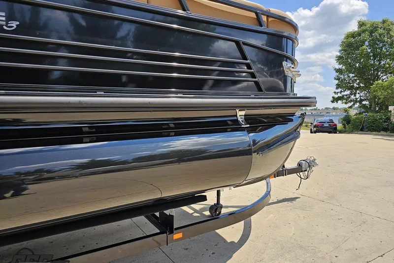 Slide: The Image of 2021 Regency 230 LE3 pontoon boat on trailer, sunny day, lakeside view. - 17