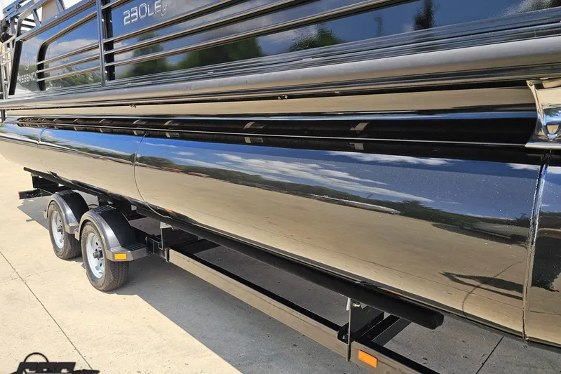 Slide: The Image of 2021 Regency 230 LE3 pontoon boat on trailer, shiny black exterior. - 18