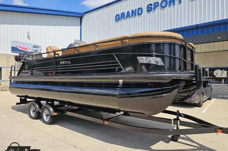 Slide: The Image of 2021 Regency 230 LE3 pontoon boat on trailer at dealership, sunny day. - 20