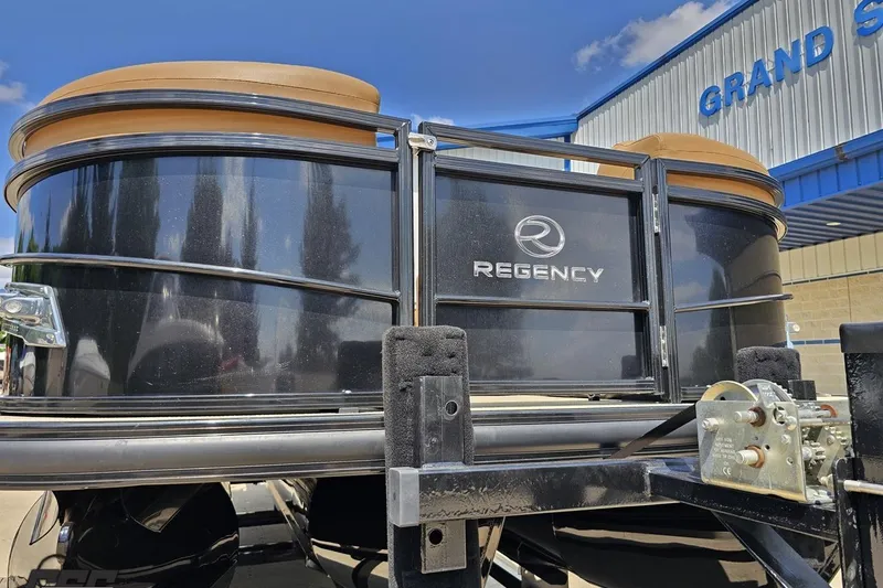 Slide: The Image of 2021 Regency 230 LE3 boat on trailer, displayed outside a showroom. - 22