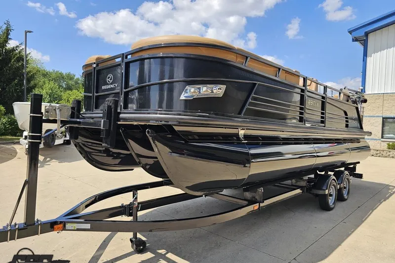 Slide: The Image of 2021 Regency 230 LE3 pontoon boat on trailer, parked outdoors under blue sky. - 26