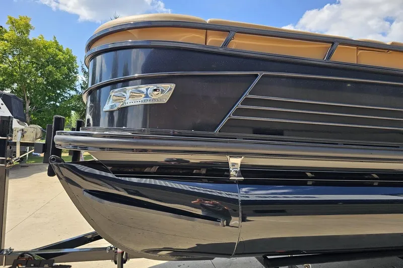 Slide: The Image of 2021 Regency 230 LE3 pontoon boat on trailer, sleek black design under blue sky. - 27