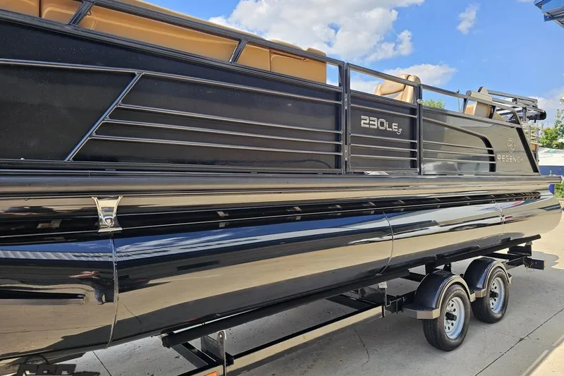 Slide: The Image of 2021 Regency 230 LE3 pontoon boat on trailer under blue sky. - 28