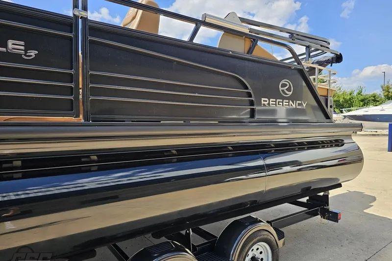 Slide: The Image of 2021 Regency 230 LE3 pontoon boat, black exterior, parked on a trailer. - 33