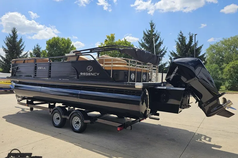 Slide: The Image of 2021 Regency 230 LE3 pontoon boat on trailer, parked outdoors under blue sky. - 39