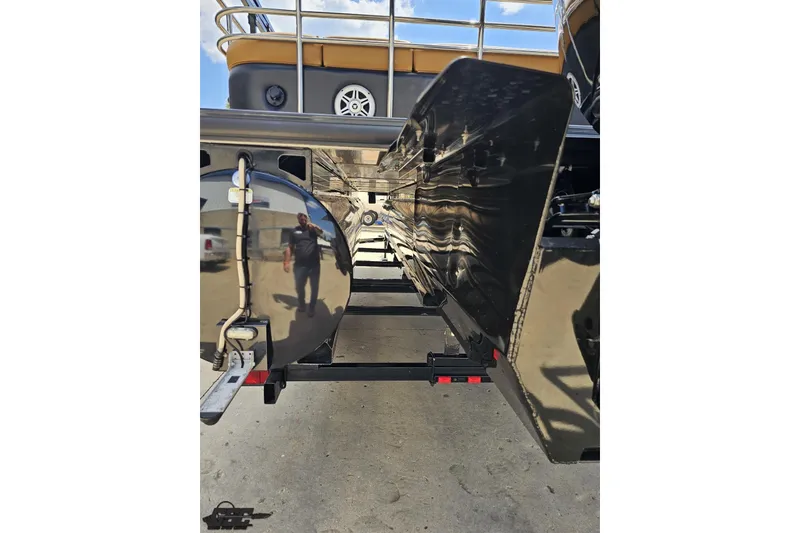 Slide: The Image of 2021 Regency 230 LE3 pontoon boat underside view with reflective surfaces and trailer. - 49