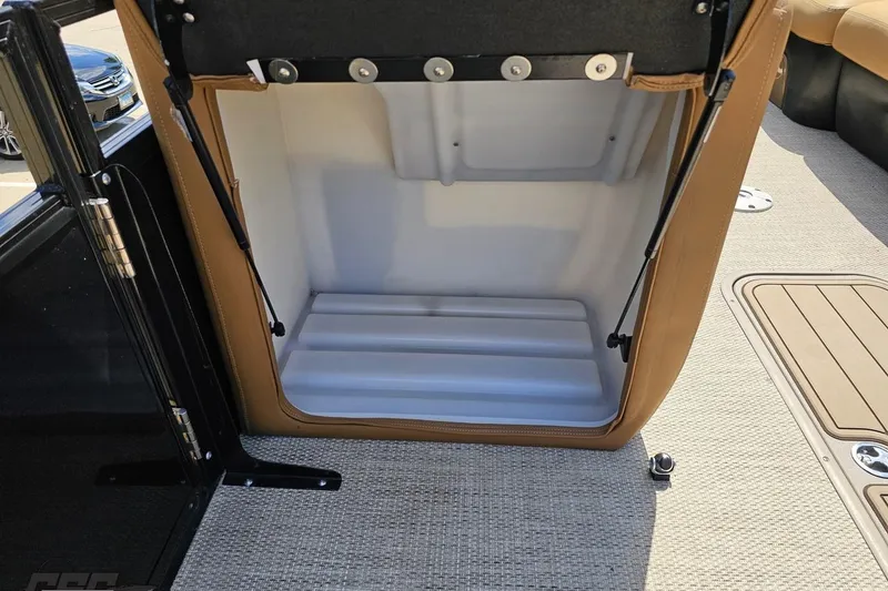 Slide: The Image of Open storage compartment in 2021 Regency 230 LE3 boat, featuring beige interior and sturdy hinges. - 69