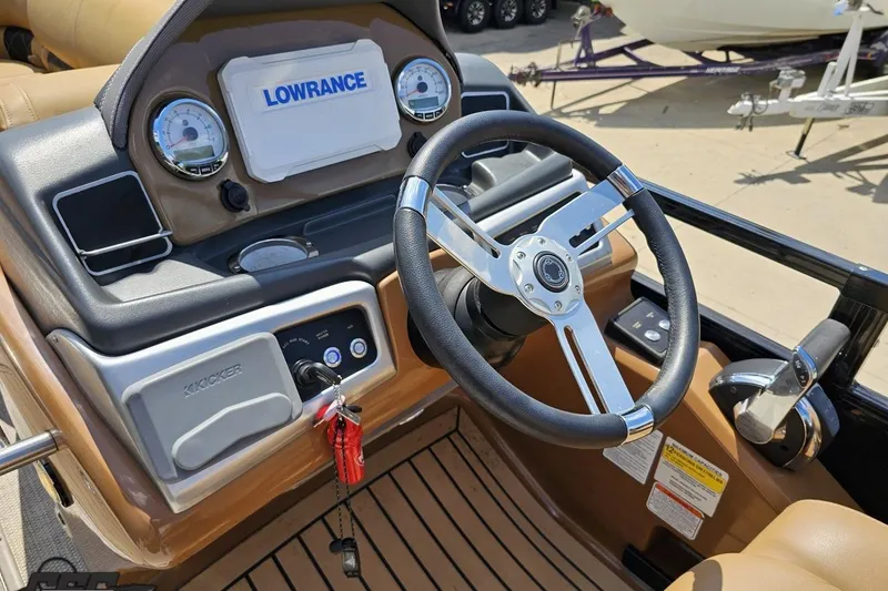 Slide: The Image of 2021 Regency 230 LE3 boat dashboard with steering wheel and Lowrance display. - 79