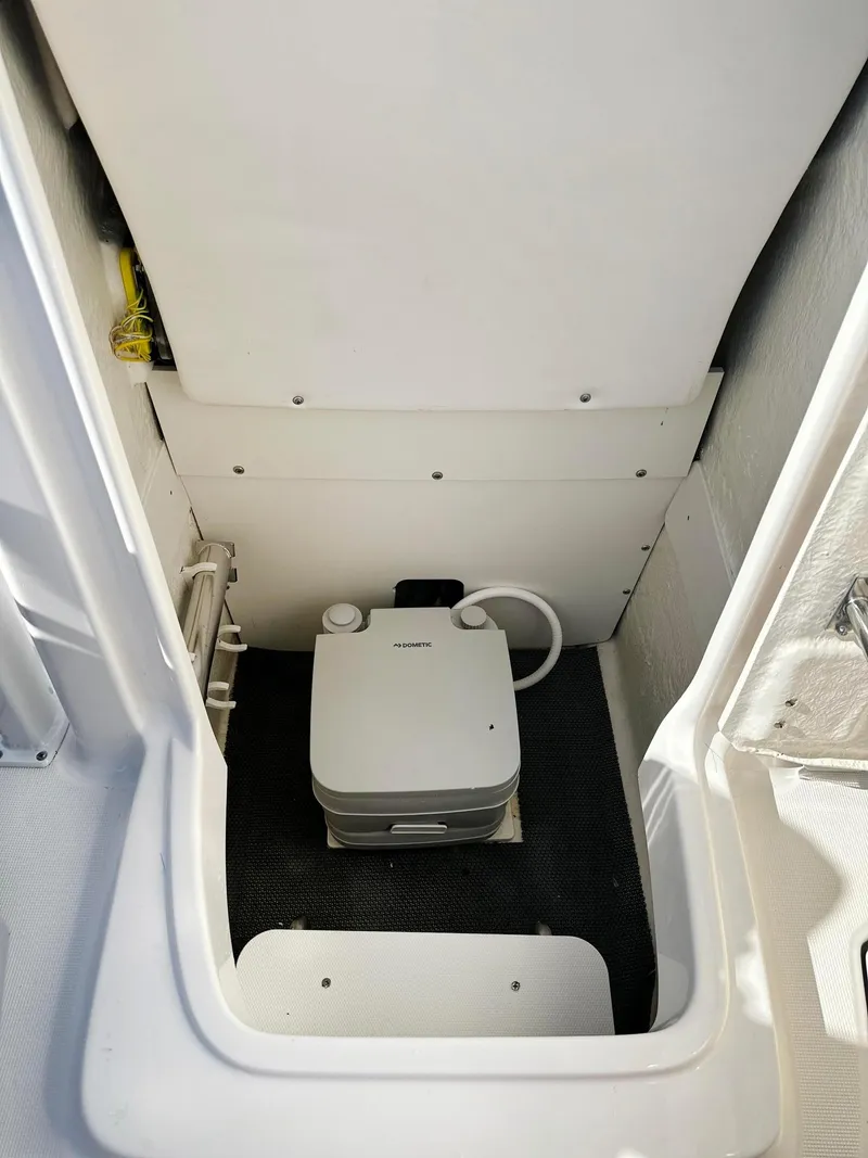 Slide: The Image of 2021 Robalo R222 Explorer boat interior with compact portable toilet. - 2