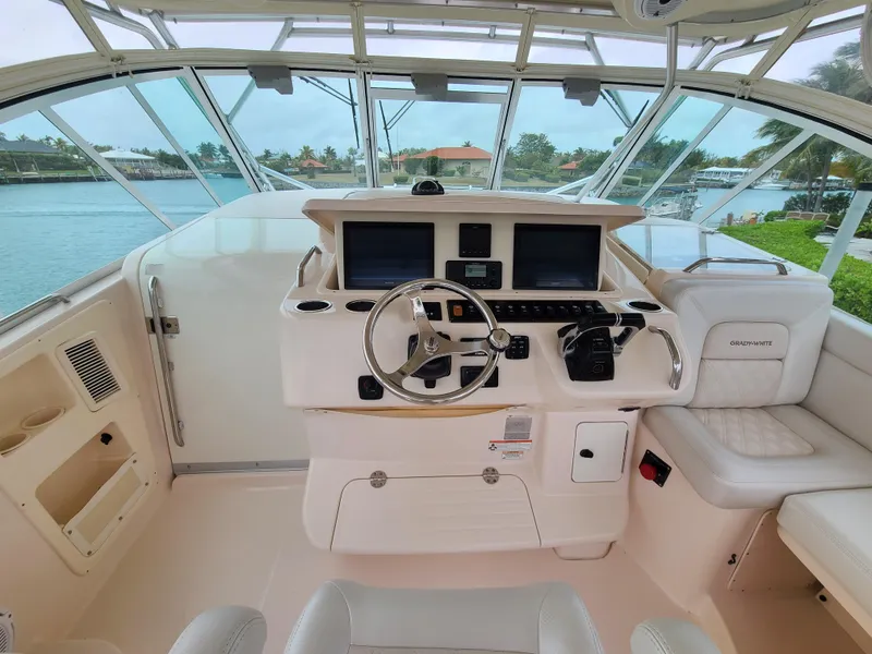 Slide: The Image of 2011 Grady-White Express 360 helm with dual screens and steering wheel, docked by the water. - 13