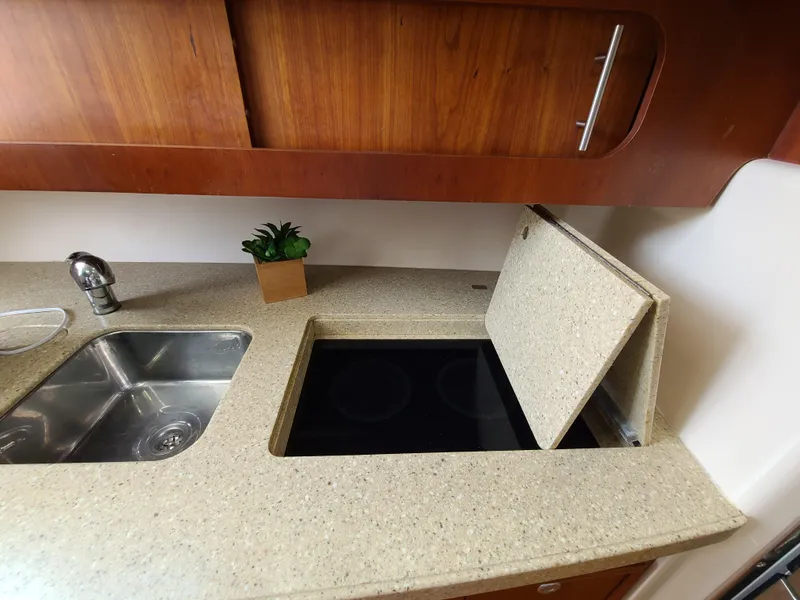 Slide: The Image of 2011 Grady-White Express 360 kitchen with sink, stove, and wooden cabinets. - 24