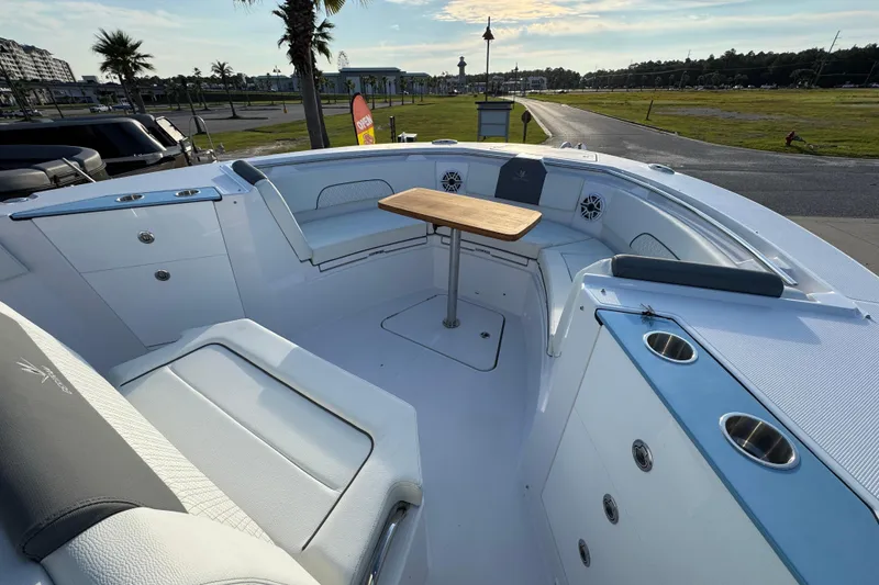 Slide: The Image of 2026 Bertram 34CC boat interior with seating and table, docked near palm trees. - 13
