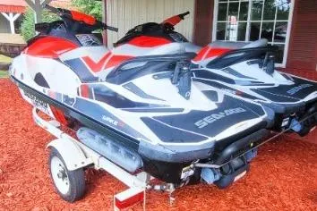 Slide: The Image of 2012 Sea-Doo Wake 155 hp jet skis on trailer, red and white design. - 2