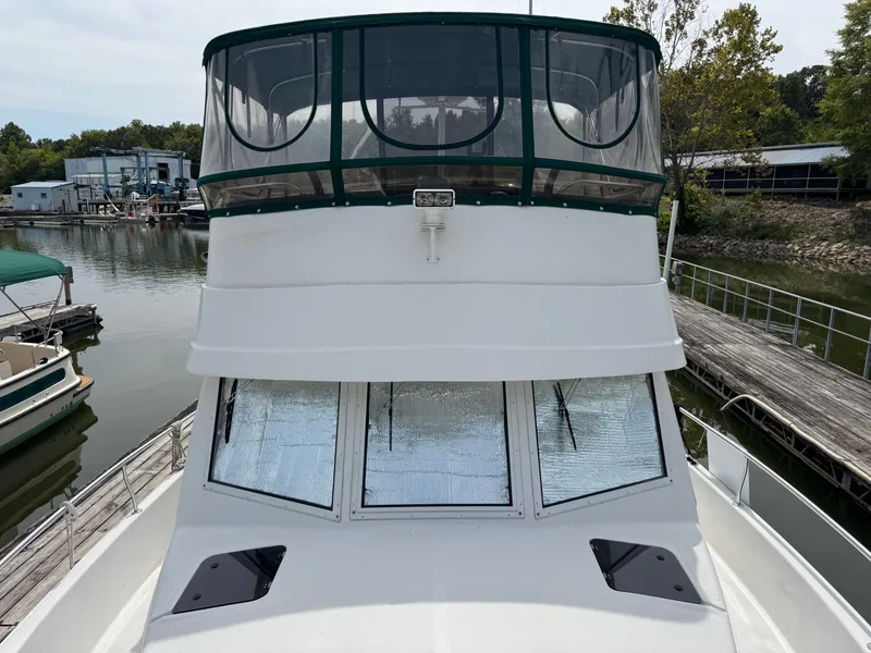 Slide: The Image of 2001 Mainship 390 boat docked at marina, featuring enclosed upper deck and sleek design. - 14