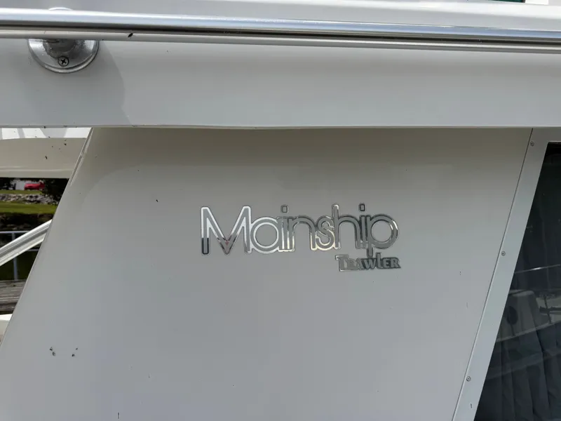 Slide: The Image of 2001 Mainship 390 Trawler boat nameplate on white exterior. - 17