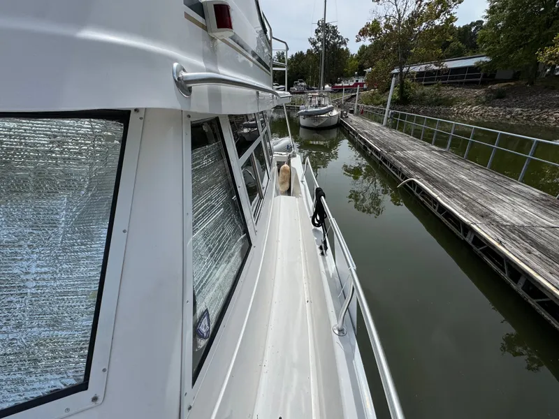Slide: The Image of 2001 Mainship 390 yacht docked at marina, side view with reflective window covers. - 18