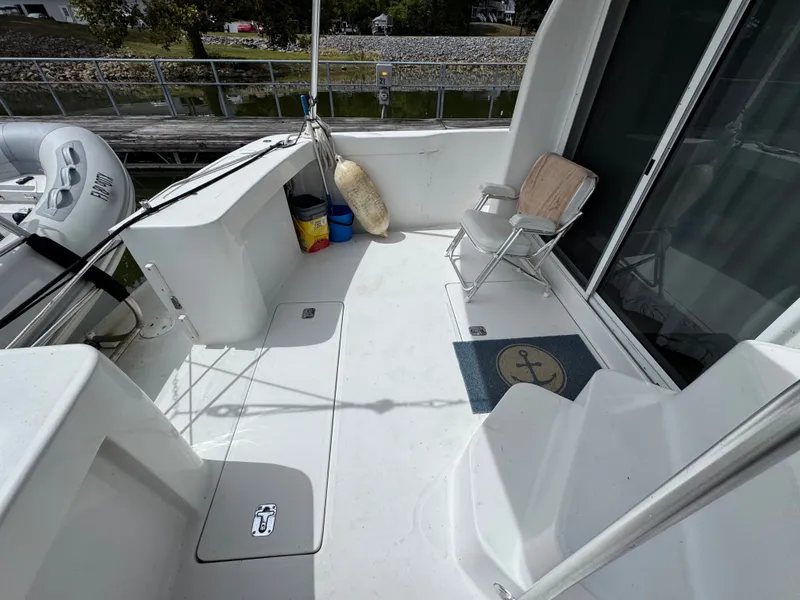 Slide: The Image of 2001 Mainship 390 boat deck with chair, mat, and docked inflatable boat. - 21