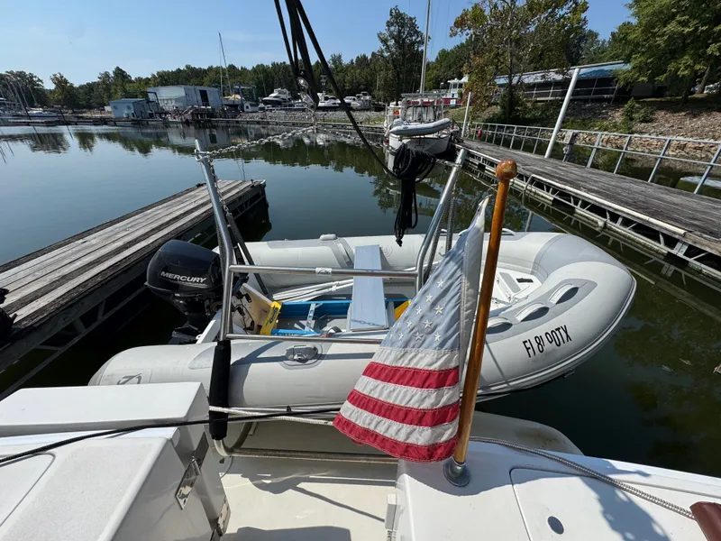 Slide: The Image of 2001 Mainship 390 docked with inflatable boat and American flag, calm marina setting. - 26