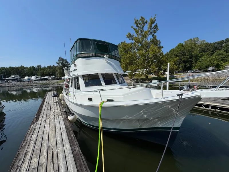 Slide: The Image of 2001 Mainship 390 docked at a marina, surrounded by calm water and trees. - 4