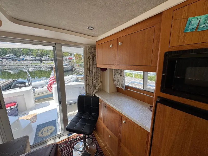 Slide: The Image of Interior of 2001 Mainship 390 yacht with wooden cabinets and marina view. - 42