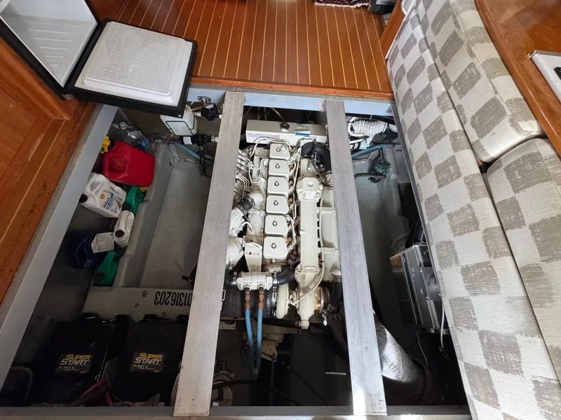 Slide: The Image of 2001 Mainship 390 engine room with visible engine, batteries, and storage compartments. - 49