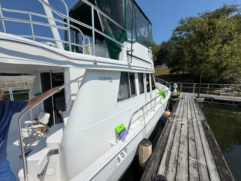 Slide: The Image of 2001 Mainship 390 yacht docked, featuring white exterior and green canopy. - 5