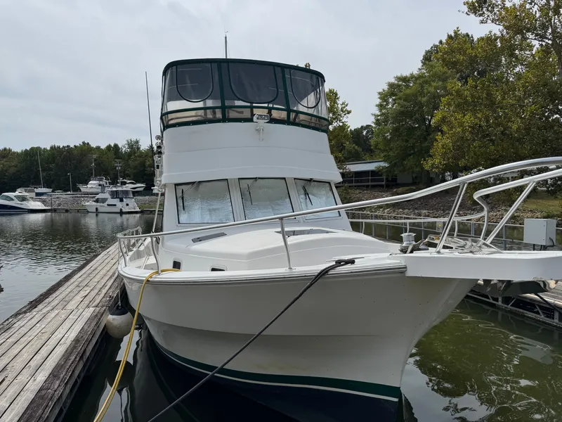 Slide: The Image of 2001 Mainship 390 yacht docked at a marina, surrounded by trees and other boats. - 6