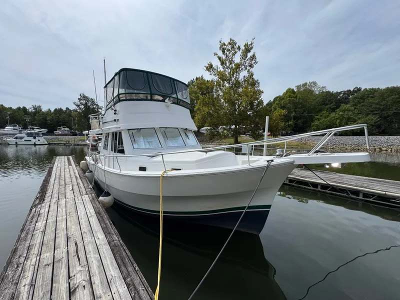 Slide: The Image of 2001 Mainship 390 docked at a marina, surrounded by calm water and trees. - 8